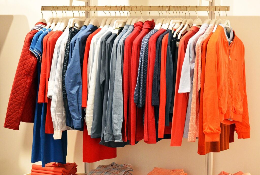 store, clothes, clothing, line, fashion, retail, clothing store, shop, shopping, consumer, purchase, department, orange, red, hangers, consumerism, spending, sale, customer, shopper, buy